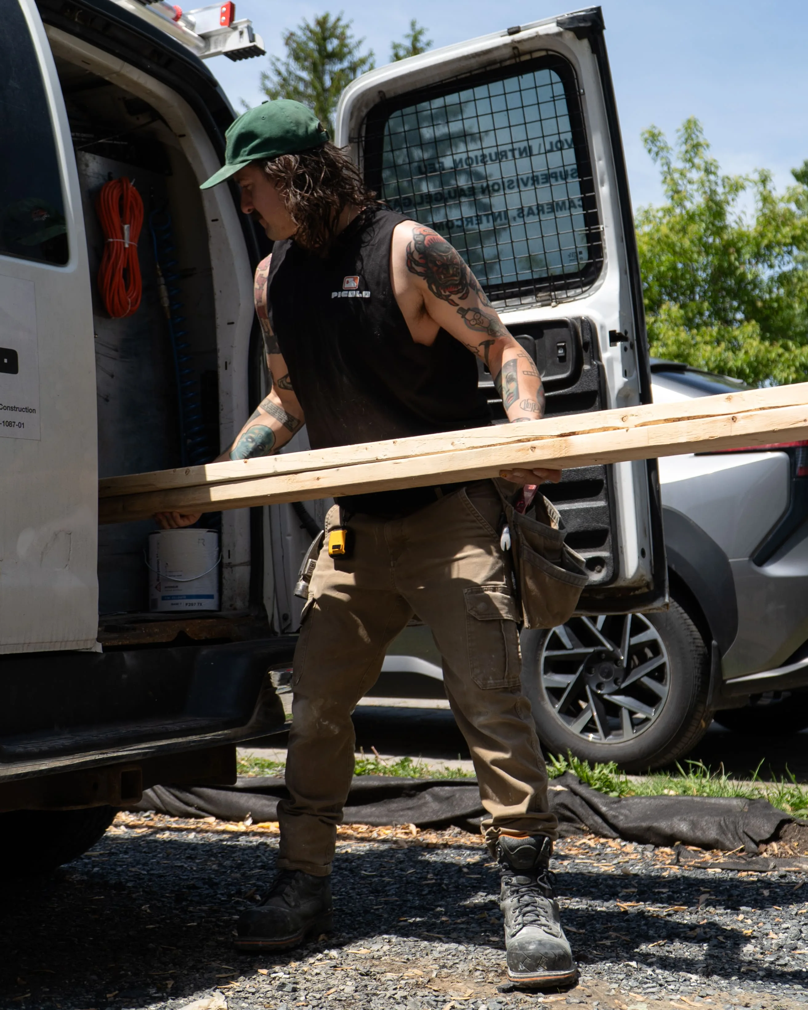 Ouvrier déchargeant des planches de bois d'une camionnette de chantier